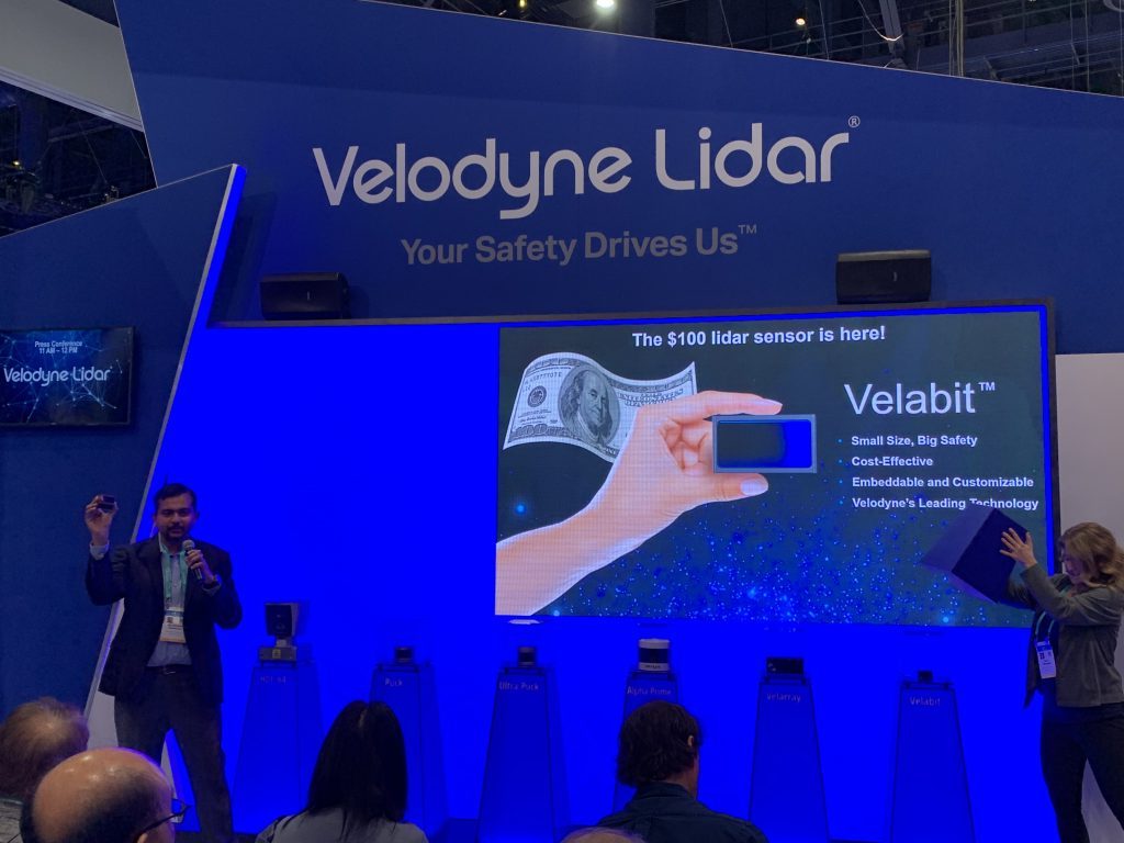 Photograph of man speaking in front of a Velodyne Lidar display